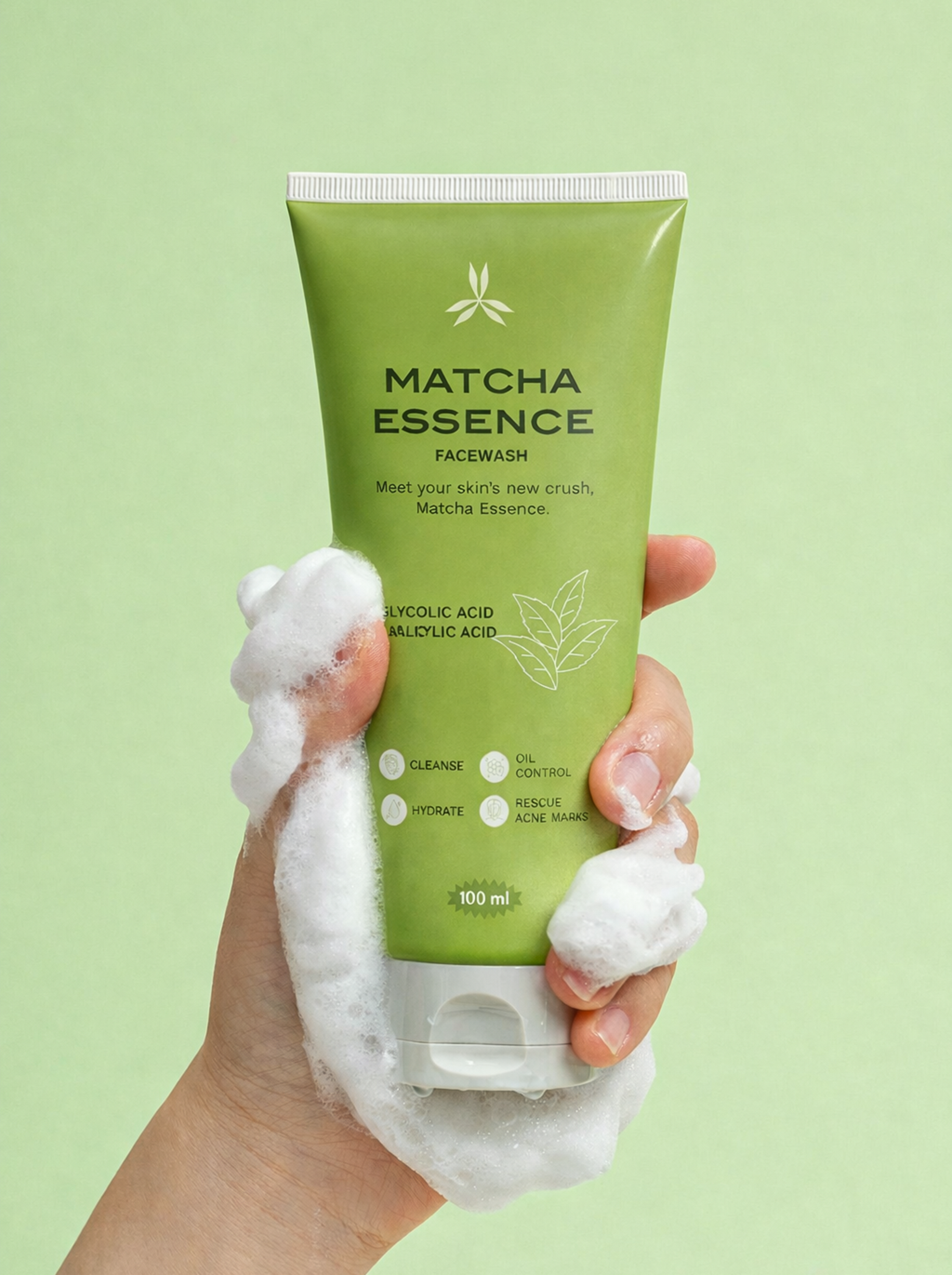 Hand holding a green Matcha Essence face wash with foam against a light green background